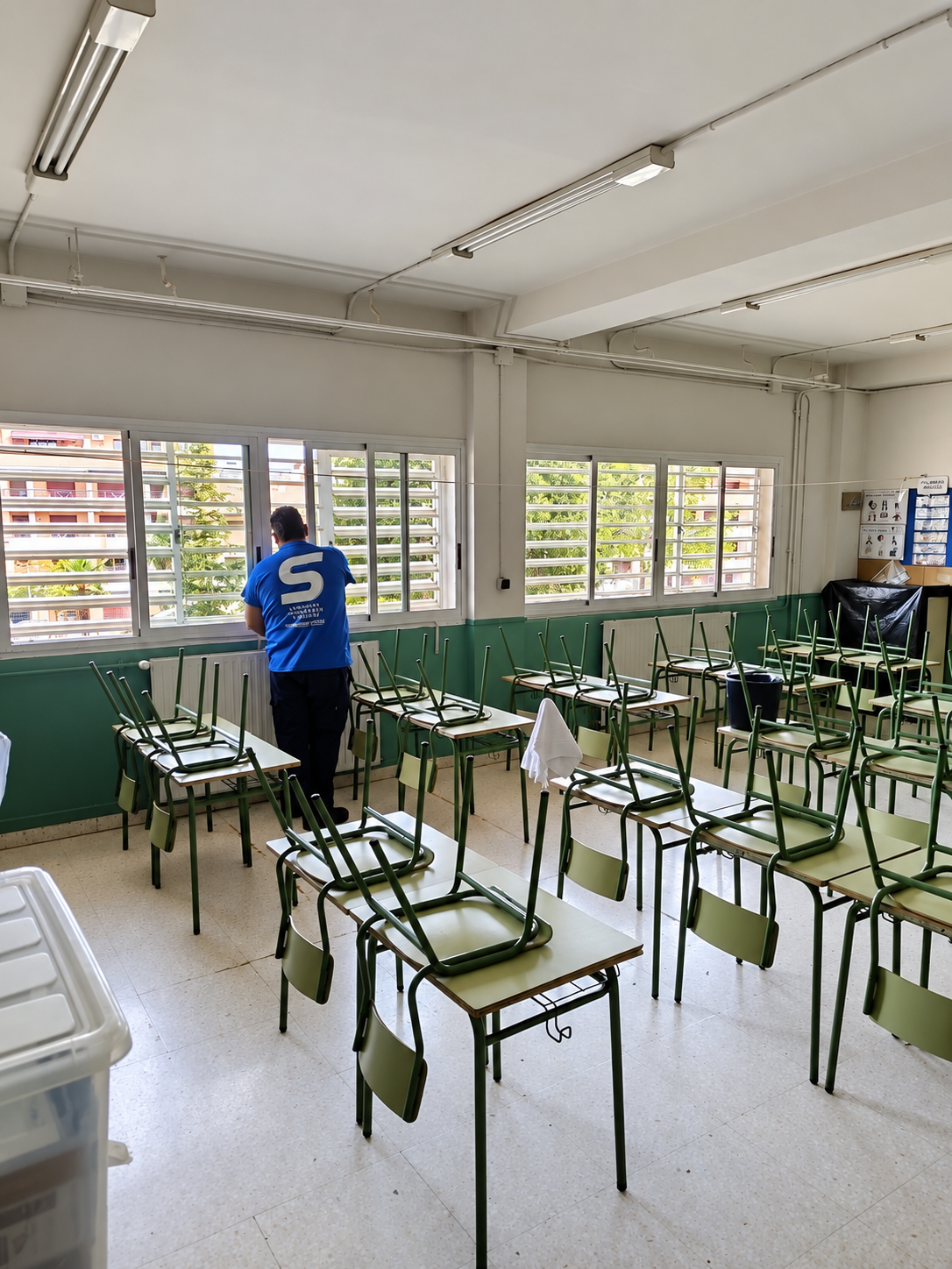 trabajador de serfey limpiando cristales en un colegio